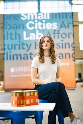 Heidi Kline poses for a photo in front of a banner that read "Small Cities Lab." She's looking pensively off into the distance