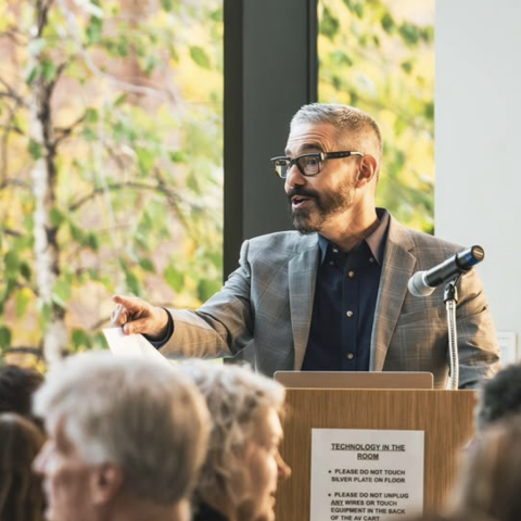 Rob Rozehnal stands at a podium and speak animately.