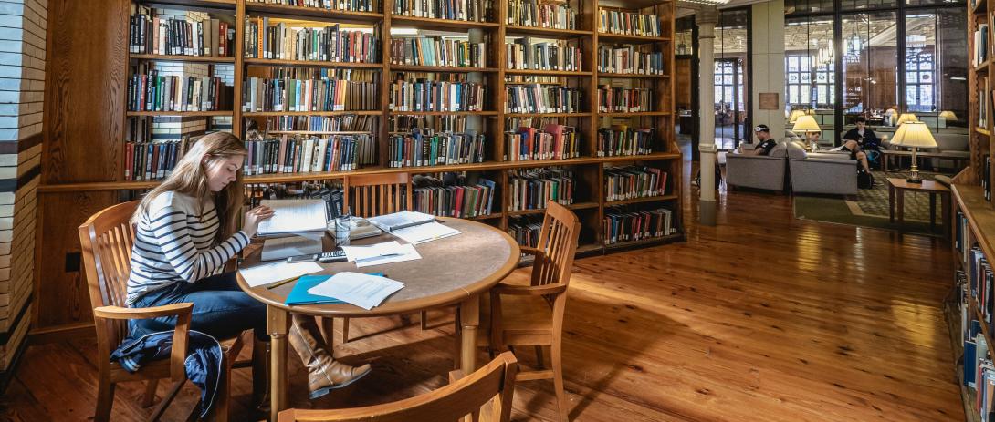 Student sits at a table with books open, studying in Linderman Library